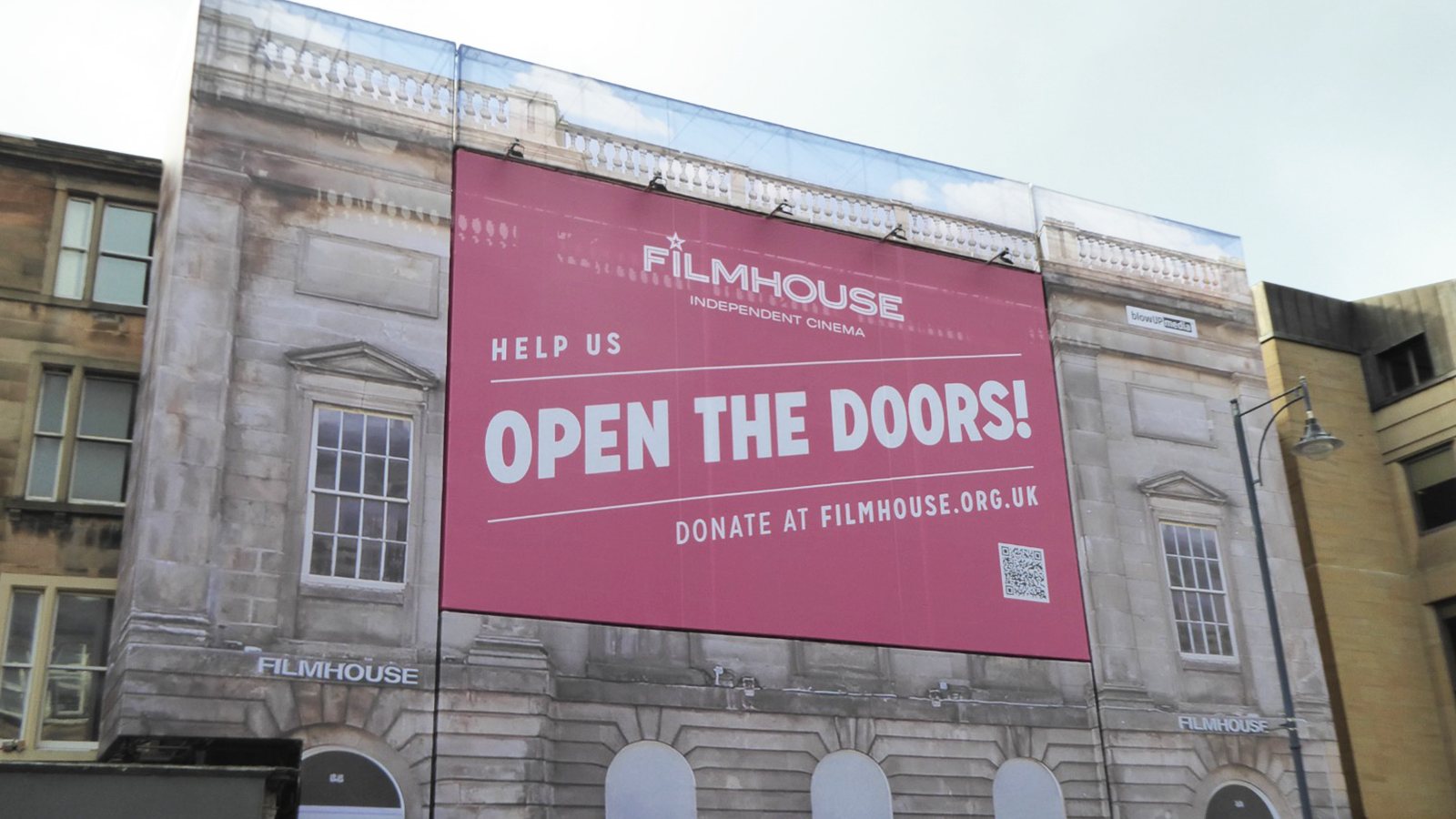 The Filmhouse cinema from the street, with a large red banner on it with white text that reads Open The Doors